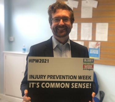 Alexander Stafford MP holding an Injury Prevention Week sign